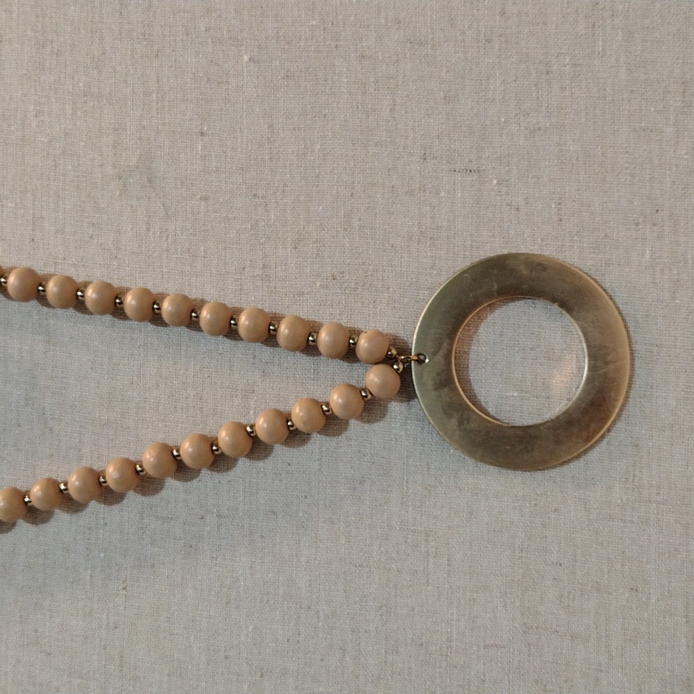 Long stand of beige and faux gold spacer beads necklace with faux gold medallion